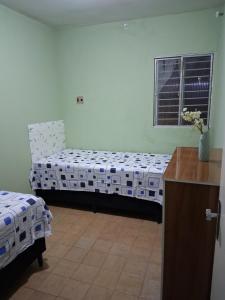 a room with two beds and a desk and a window at Quarto Residencial in Recife