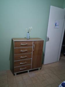 a dresser with a vase on it next to a door at Quarto Residencial in Recife