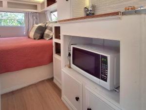Dormitorio pequeño con cama y microondas en Vintage Coral Green, en Nelly Bay