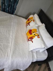 カンパラにあるMosh apartmentsのくまのプーさんの枕が置かれた白いベッド