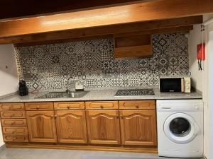 a kitchen with a sink and a washing machine at Casa Herbarium in Prazeres