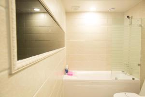 a bathroom with a tub and a toilet and a mirror at Major Hotel 2 in Jeju