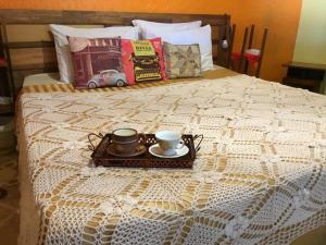 a bed with a tray with two cups and books at Casa Refúgio Cataratas - Perto das Principais Atrações e do Aeroporto in Foz do Iguaçu