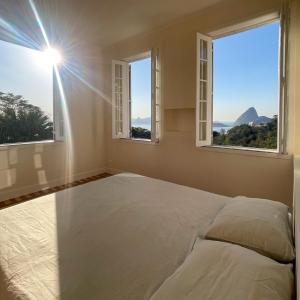 a bedroom with two windows and a white bed at Casa Rocha in Rio de Janeiro