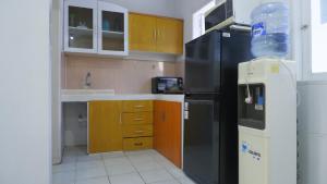 a kitchen with a black refrigerator and wooden cabinets at Villa Dalia Puncak H1-26 in Cikundul