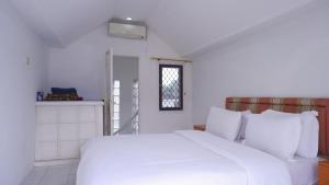 a white bed in a room with a window at Villa Dalia Puncak H1-26 in Cikundul