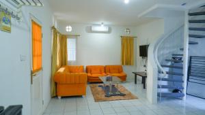 a living room with an orange couch and a staircase at Villa Dalia Puncak H1-26 in Cikundul