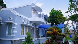 a blue house with a balcony and trees at Villa Dalia Puncak H1-26 in Cikundul