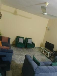 a living room with two blue couches and green chairs at Impeccable 2chambres salon centre ville de cotonou in Godomey +8 photos