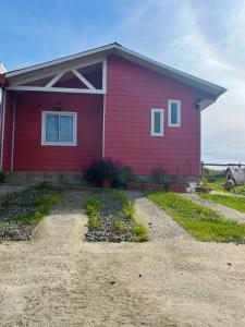 a red house with a gravel driveway in front of it at Cabañas Mongetum in Constitución