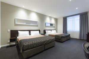 a hotel room with two beds and a window at Great Southern Hotel Melbourne in Melbourne