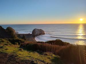 a sunset on a beach with a large rock in the ocean at Cabañas Mongetum in Constitución