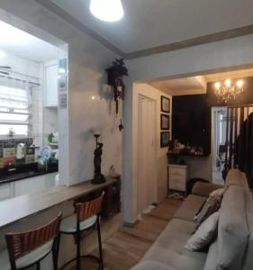 un salon avec un canapé et une cuisine dans l'établissement Lindo apto frente mar em região privilegiada de Santos, à Santos
