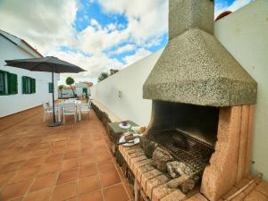 a patio with an outdoor fireplace and a table with an umbrella at Spacious Holiday Home in La Oliva in Villaverde