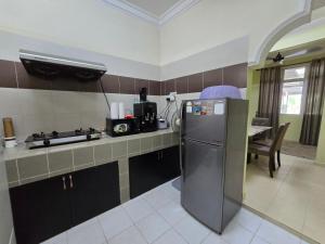 a kitchen with a stainless steel refrigerator and a table at Dunia Kanak Kanak Homestay in Kota Bharu