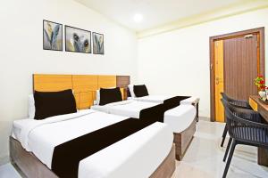 two beds in a room with a table and chairs at Super Townhouse Kondapur Near Botanical Garden Formerly RRR Inn in Hyderabad