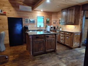a kitchen with wooden cabinets and a black refrigerator at TheGapCabin in Buffalo Gap