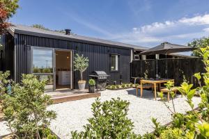 ハブロック・ノースにあるPeaceful Escape Close to Town - The Sanctuary Studioのテーブルと傘のある黒い家のある裏庭