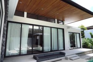 una casa con ventanas negras y un sofá en Luxurious villa By IBG Property, en Ban Pak Lak