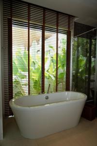 Una bañera en un baño con una ventana grande. en Luxurious villa By IBG Property, en Ban Pak Lak