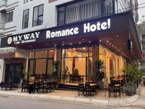 a man standing outside of a restaurant with tables and chairs at Romance hotel in Cat Ba