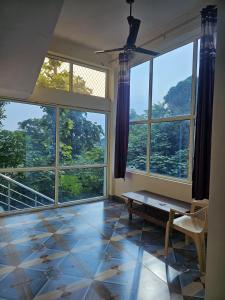 a living room with large windows and a table at Corbett view homestay in Belparāo
