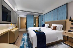 a bedroom with a large white bed and a kitchen at Echarm Hotel 1st Affiliated Hospital of Suzhou University Pingjiang in Suzhou +262 photos