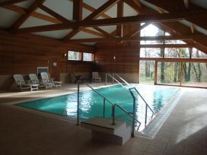 a large swimming pool in a building with a large window at Logis Hôtel Le Bois Dormant-Hôtel Restaurant & Spa in Champagnole