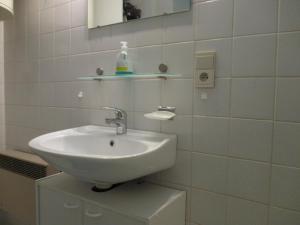 a white bathroom with a sink and a mirror at Studio with sea view and panoramic view in Bredene in Bredene
