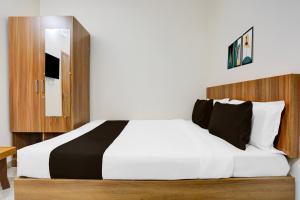 a bedroom with a white bed with a wooden headboard at Hotel O by OYO Saptagiri Comforts in Bangalore