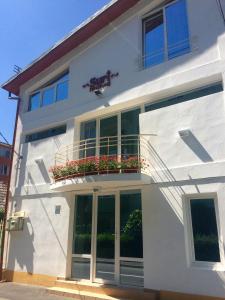 a white building with windows and a balcony at Suri Guesthouse in Braşov