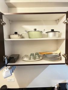 a kitchen shelf with pots and pans and plates at Aurora Escalades Residences in Manila