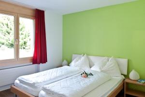 a bedroom with a large white bed with a window at Pollux Family Apartment in Zermatt