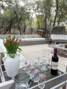 a table with glasses and a bottle of wine and a vase with flowers at InniBos Marloth Park in Marloth Park +55 photos