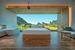 a bedroom with a bed and a large window at 桂林阳朔良宿 LS Hotel Liangsu Yangshuo in Gaotian