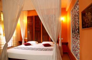 a bedroom with a bed with white sheets and red pillows at Villa Ceylon in Katunayaka