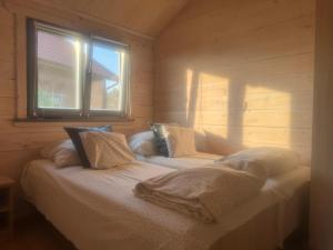 a bed sitting in a room with a window at Domki Nad Stawem Mazury D4 in Mrągowo