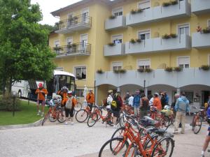 eine Gruppe von Menschen steht mit Fahrrädern vor einem Gebäude in der Unterkunft Vitalé Hotel Daniela in Levico Terme