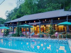 a hotel with a swimming pool in front of a building at Woodstock Beach Camp in Cat Ba