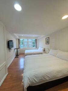 a bedroom with two beds and a flat screen tv at Maria Hotel in Zhongzheng +12 photos