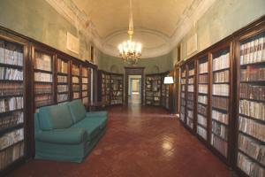 eine Bibliothek mit einem blauen Stuhl in einem Raum mit Büchern in der Unterkunft Villa Malacari in Offagna