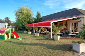 ein Restaurant mit einem Tisch und einem Spielplatz im Hof in der Unterkunft As Hotel Orléans Nord Artenay in Artenay