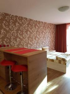 a room with a desk and a bed with red stools at Apartment Kraev in Primorsko