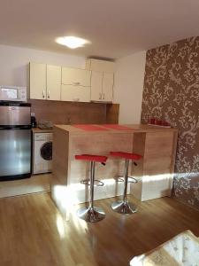 een keuken met een aanrecht met twee rode krukken bij Apartment Kraev in Primorsko