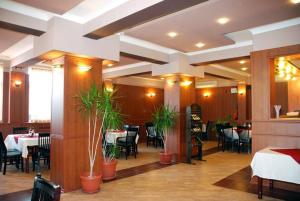 una sala da pranzo con tavoli, sedie e piante di Hotel Kibor a Gŭlŭbovo