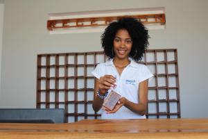 a woman standing at a table holding a book at Las Rochas Mindelo Aparthotel in Mindelo