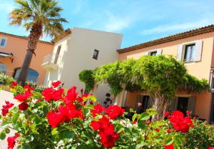 ロクブリューヌ・シュル・アルジャンにあるLe Daya Hotel et Spaの赤い花とヤシの木のある家
