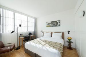 a bedroom with a large white bed and a desk at Lily & Bloom Boutique Hotel in Tel Aviv