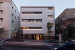 un grand bâtiment blanc avec des voitures garées dans la rue dans l'établissement Lily & Bloom Boutique Hotel, à Tel Aviv