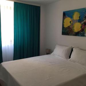 ein Schlafzimmer mit einem weißen Bett und einem grünen Vorhang in der Unterkunft Apartamente Seashells Mamaia Nord in Mamaia Nord – Năvodari